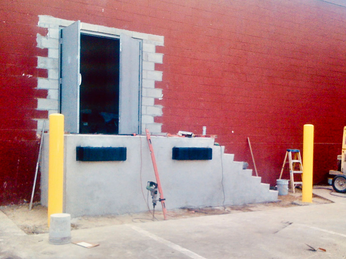 Completed commercial loading dock with steel doors and safety bollards in Stoughton, MA