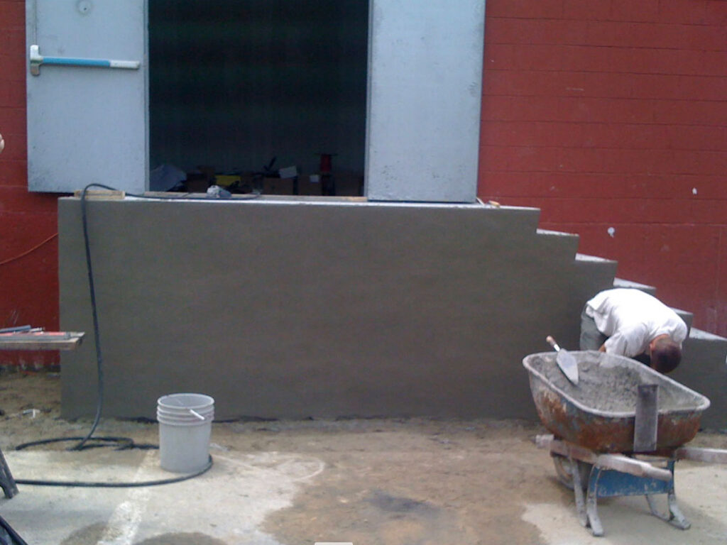 Mason finishing concrete block loading dock walls in Stoughton, MA