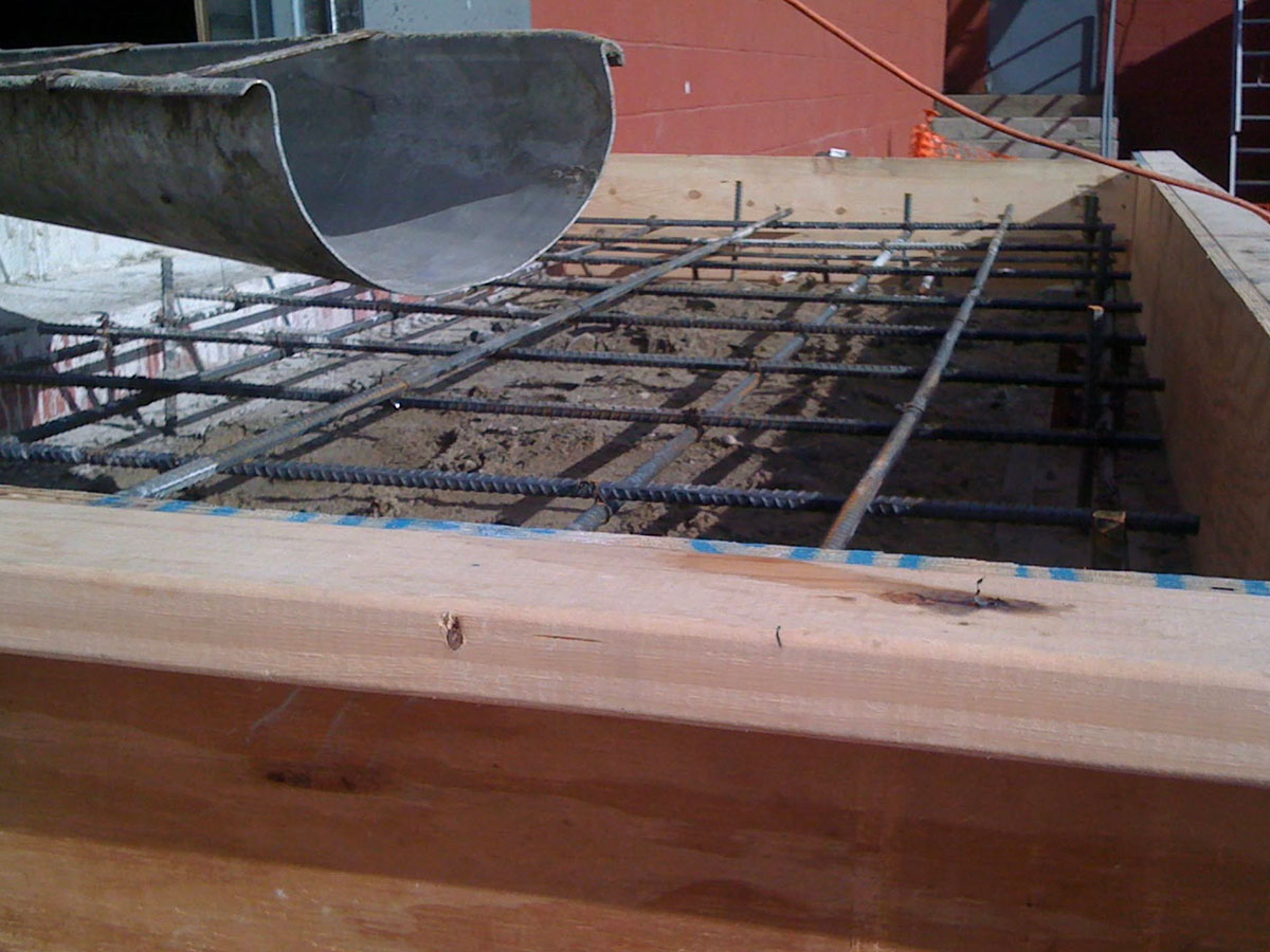 Concrete being poured over steel rebar for a commercial loading dock landing