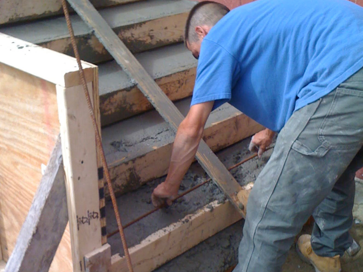 Mason placing concrete in reinforced stair forms during commercial entry construction in Stoughton, MA