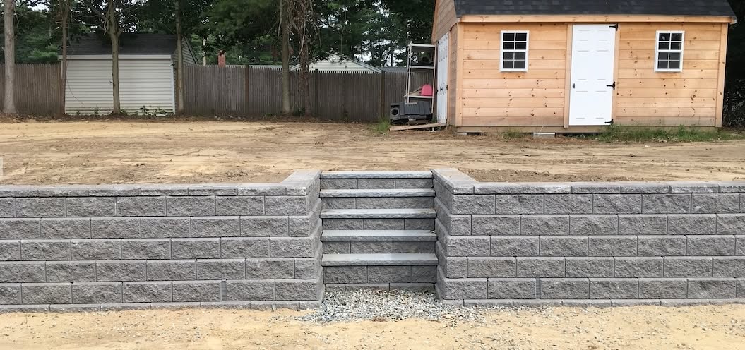 Granite steps integrated into an Allan Block retaining wall in Raynham, MA