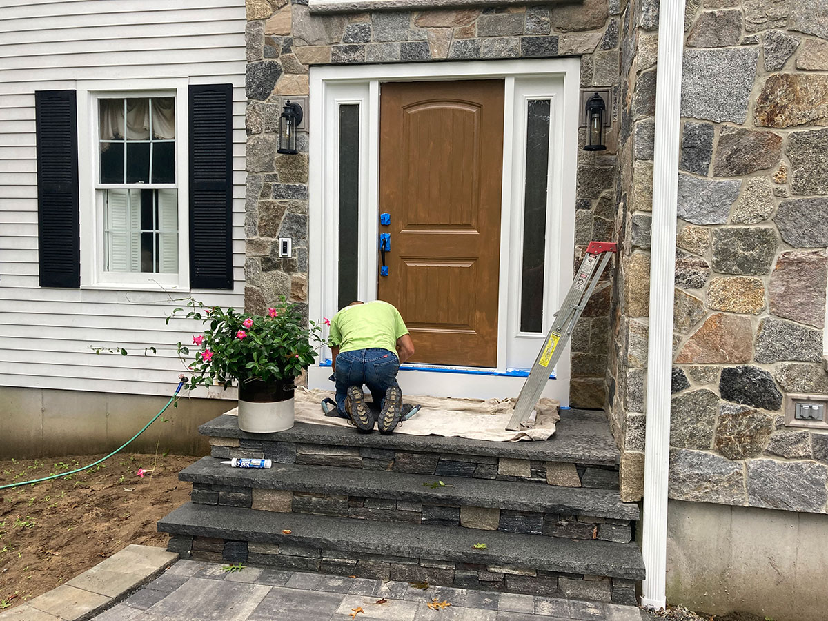Cornerstone mason completing final detail work around the stone veneer front entrance