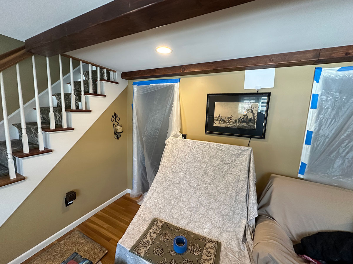 Living room furniture and windows covered before fireplace demolition and stone veneer installation