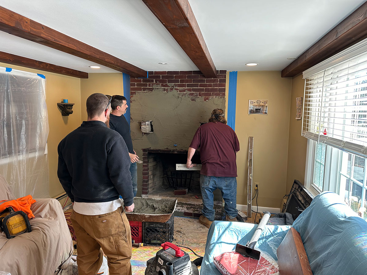 Cornerstone masons preparing the original brick fireplace with a mortar base coat in Raynham, MA