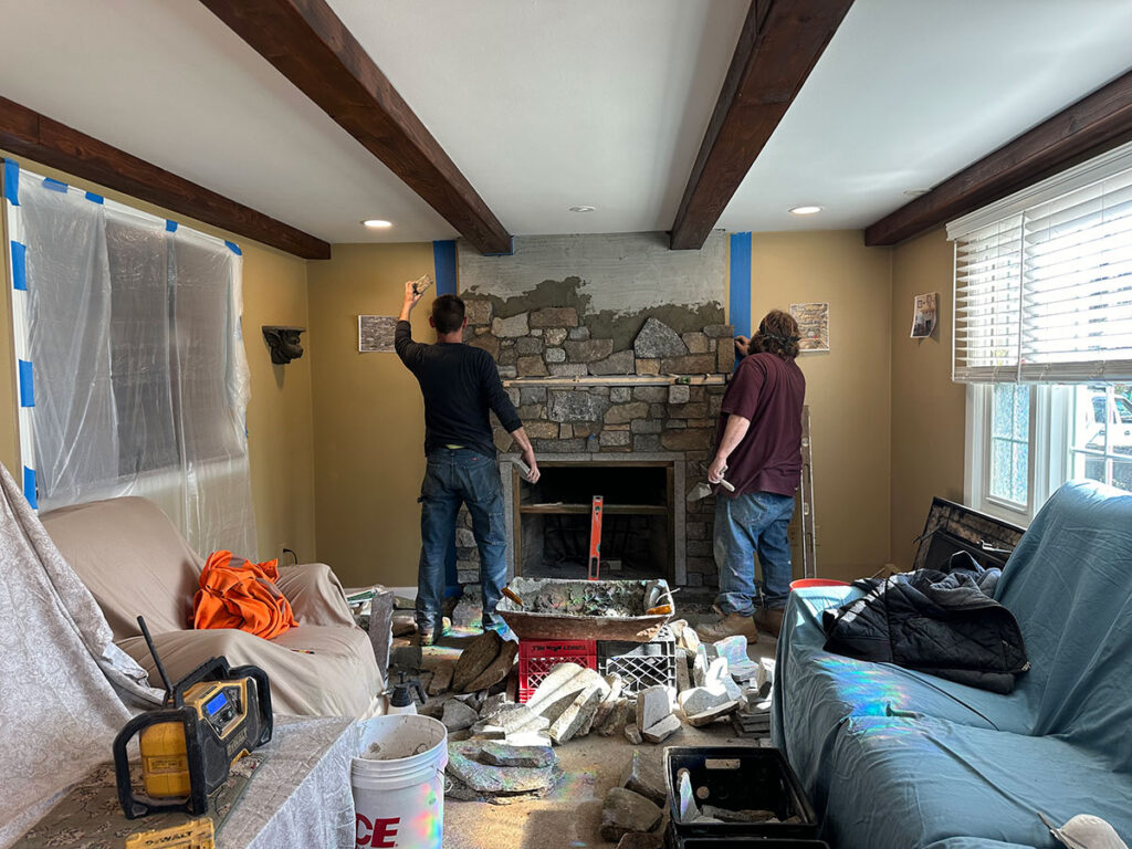 Masons installing Lexington Blend stone veneer above the custom granite fireplace surround