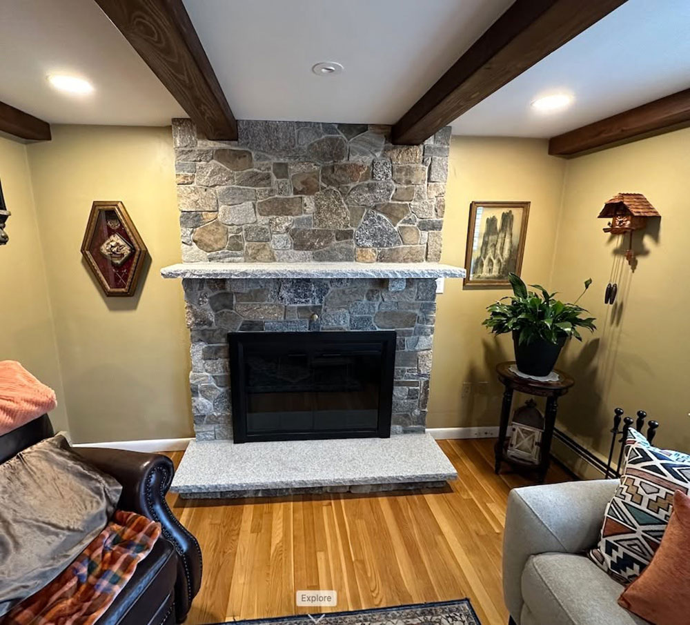 Wide room view of an interior stone fireplace with coordinated granite details