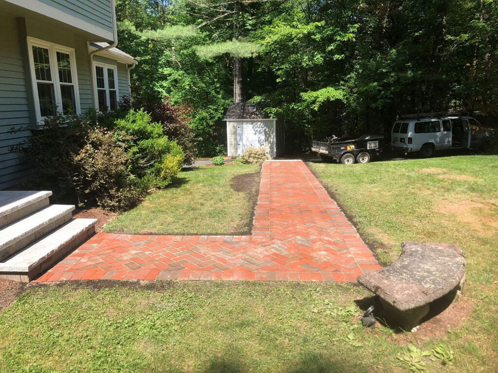 A view from the home shows the rebuilt walkway extending through the front landscape.