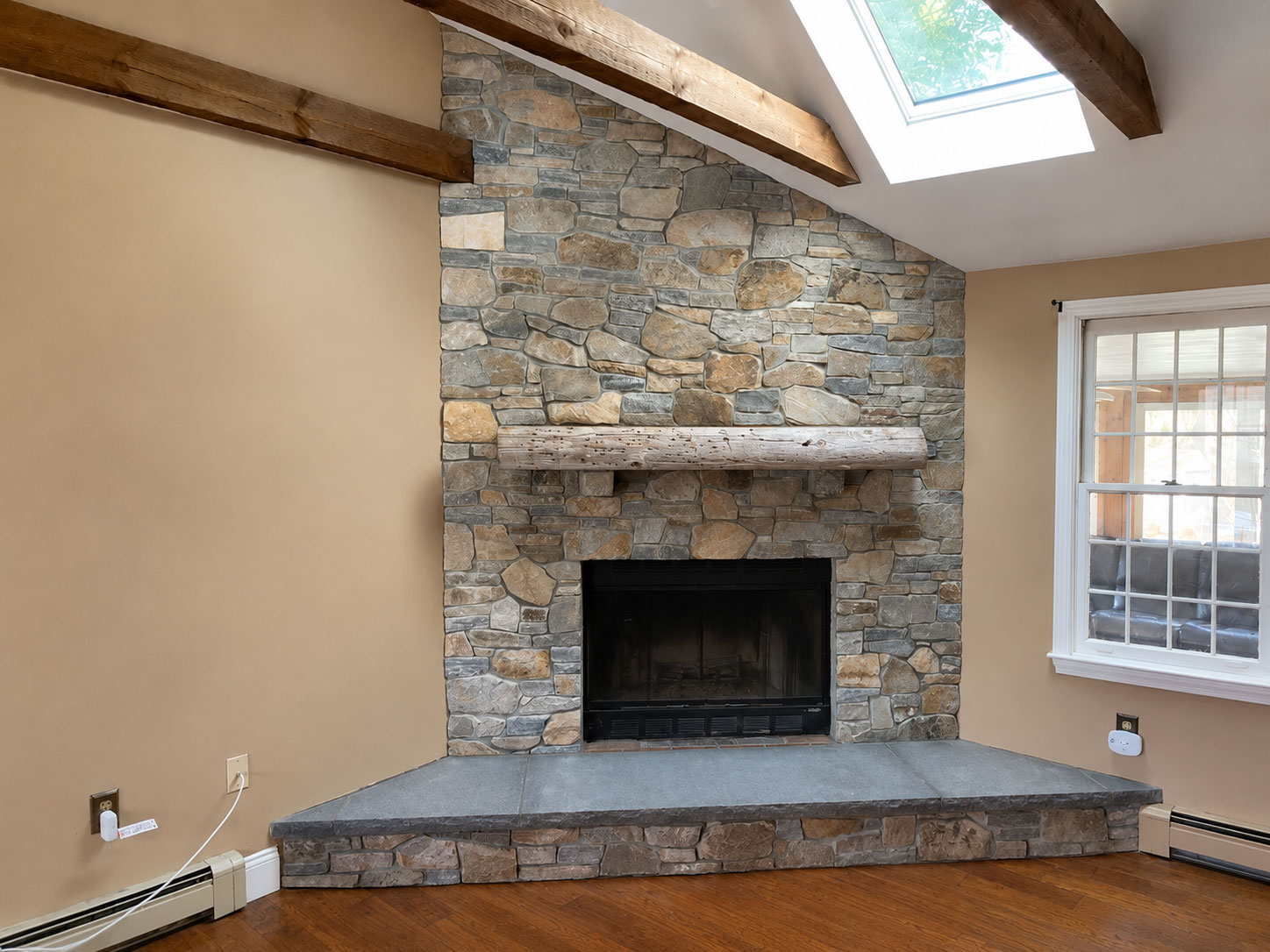 Interior stone veneer fireplace refacing with a bluestone hearth in Pembroke, Massachusetts