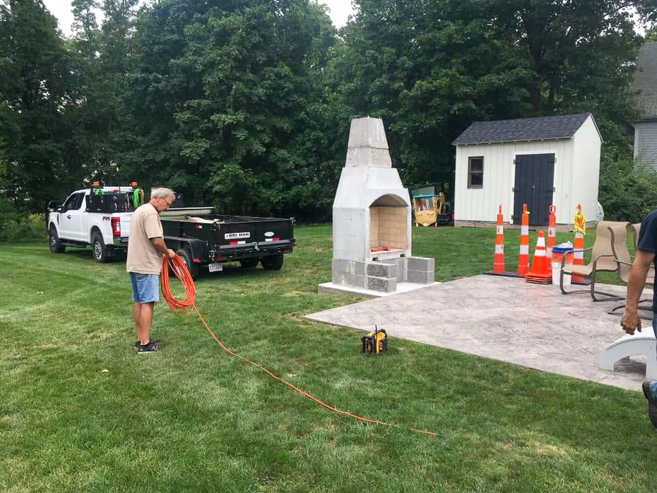 Masonry core of a custom outdoor fireplace under construction beside an Easton, MA patio