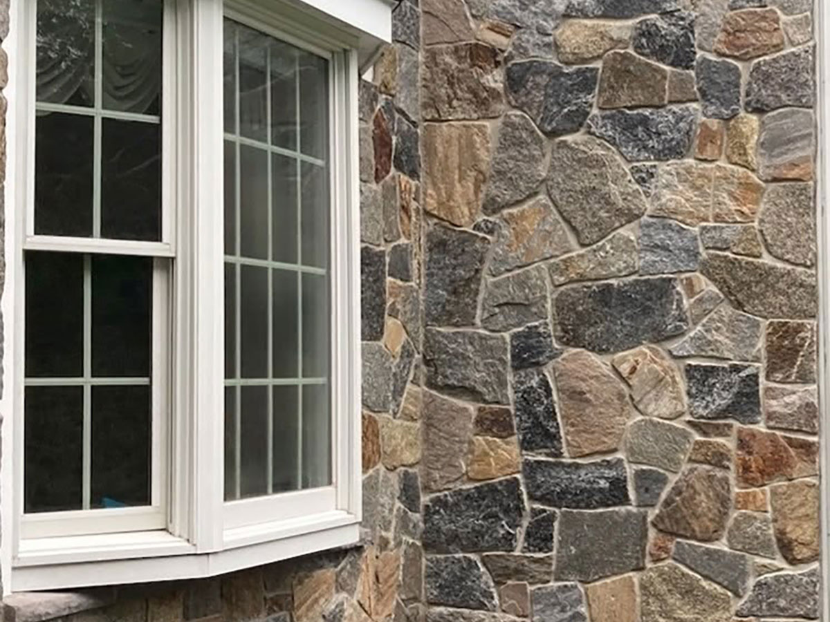 Close view of completed Connecticut Blend natural stone veneer across the home’s front bay window in mansfield ma