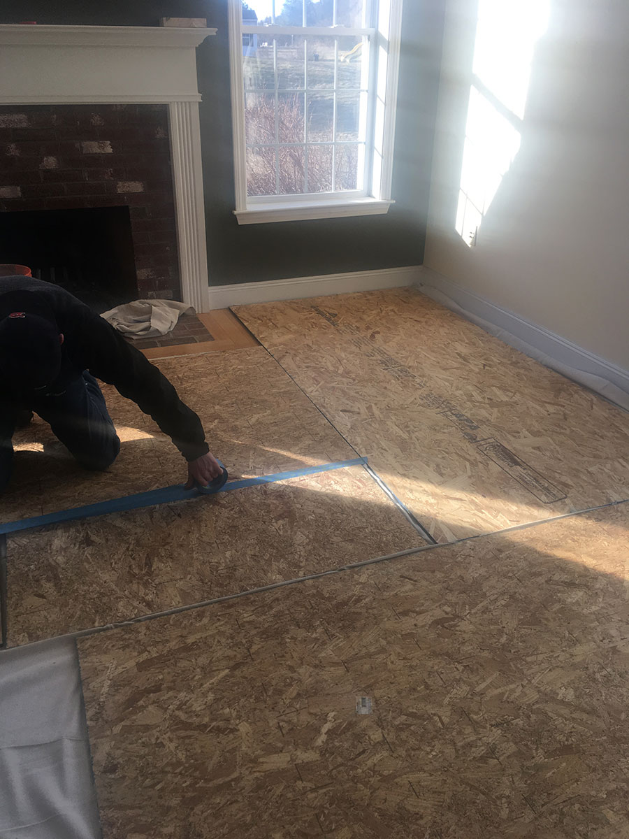 Protective floor panels being secured before interior fireplace masonry work