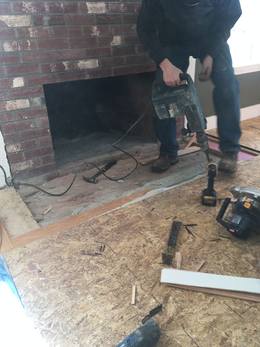 Mason removing the existing fireplace hearth with a demolition hammer