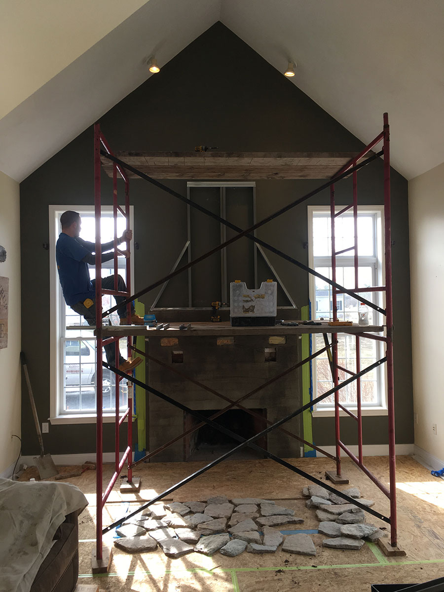 Scaffolding and natural stone prepared for a floor-to-ceiling fireplace installation in Stow, MA