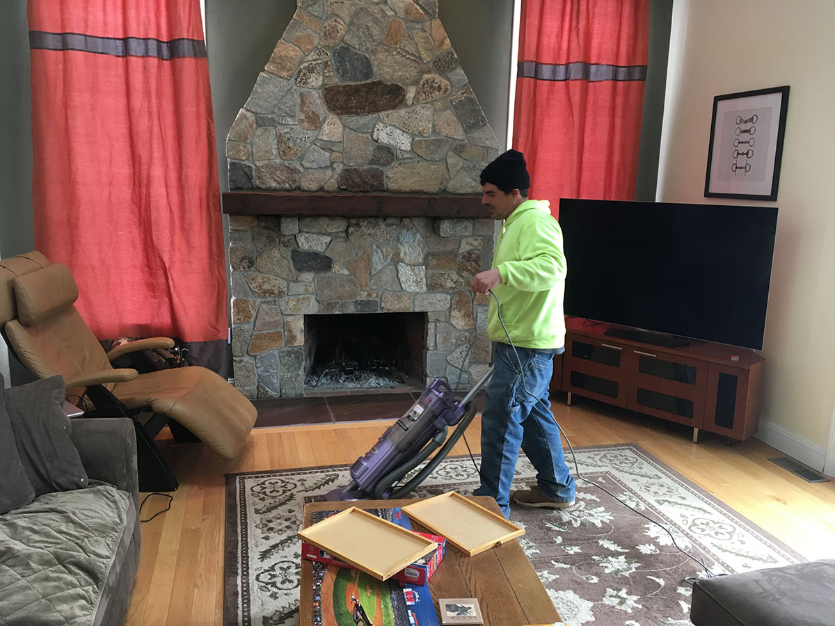 Cornerstone team member cleaning the occupied living room after the stone fireplace installation