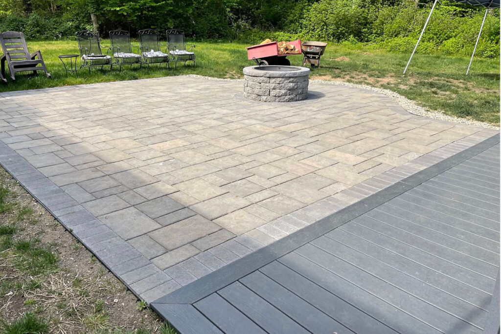 Large backyard paver patio with a circular masonry fire pit