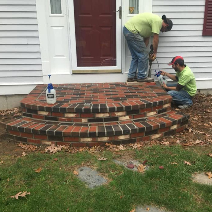 two masons repairing brick front steps