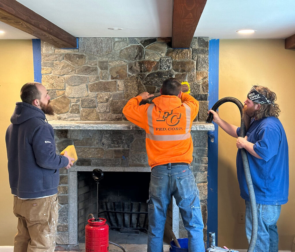 three workers cleaning fireplace after thin stone veneer installation